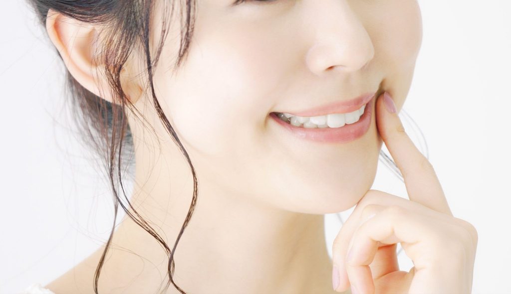 口元に指を当てて笑顔の女性