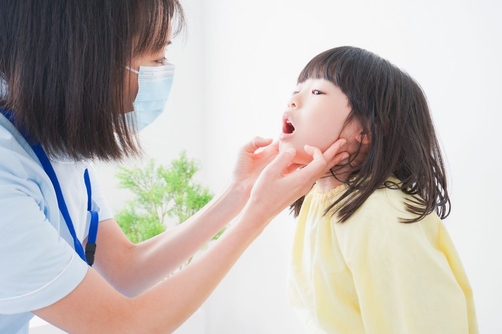 子どもの口の中をチェックしている歯科医療従事者の女性