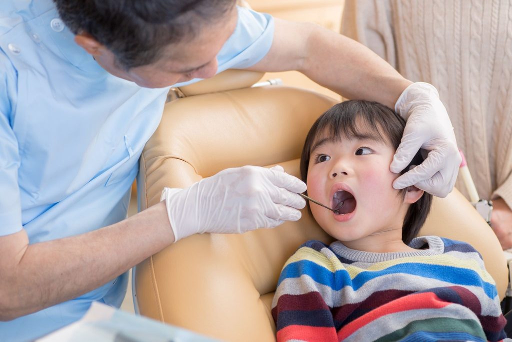 子どもの口の中をチェックしている矯正歯科医