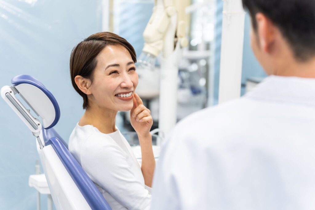 矯正歯科で診療チェアに座って矯正歯科医に笑顔を向ける女性