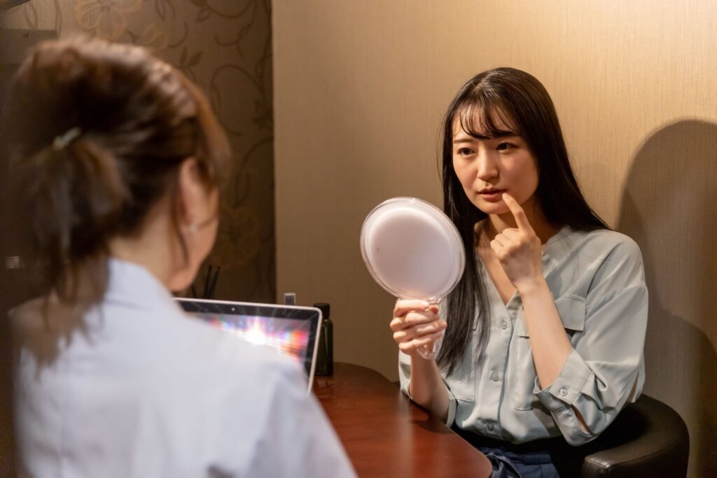鏡を持ってガミースマイルについて医師に相談している女性