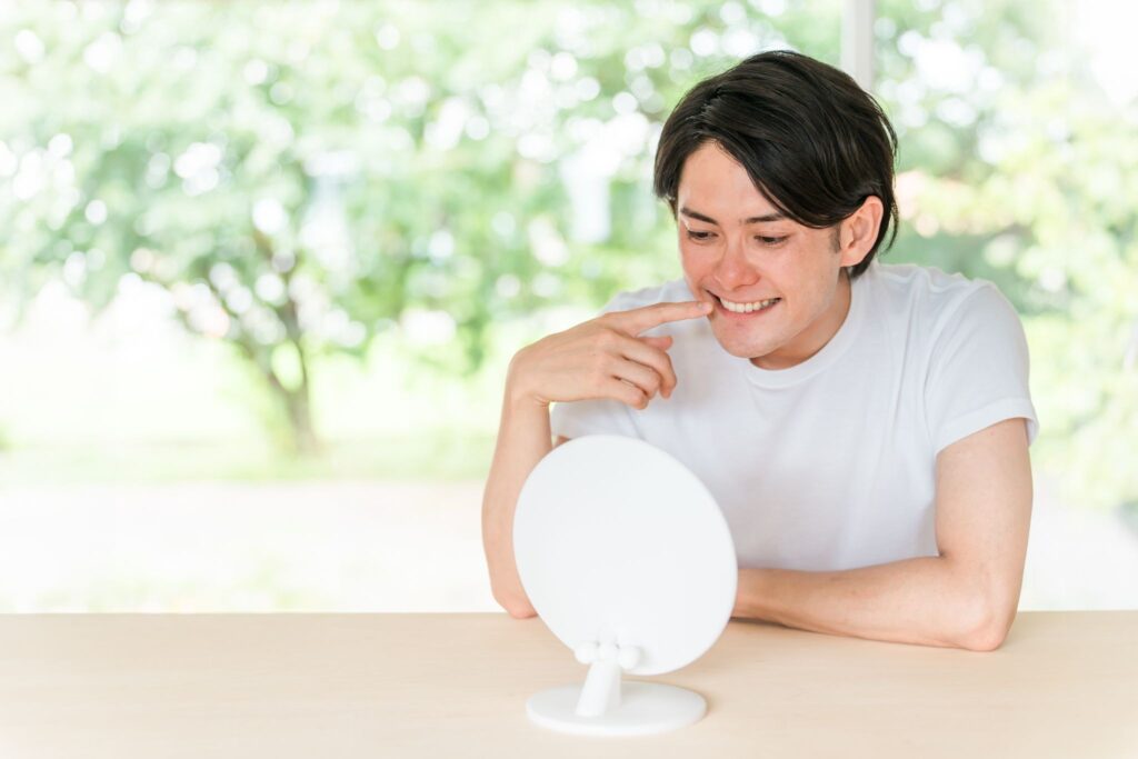 歯を気にして鏡を見ている男性