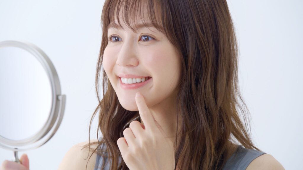 鏡で歯を見て笑顔の女性