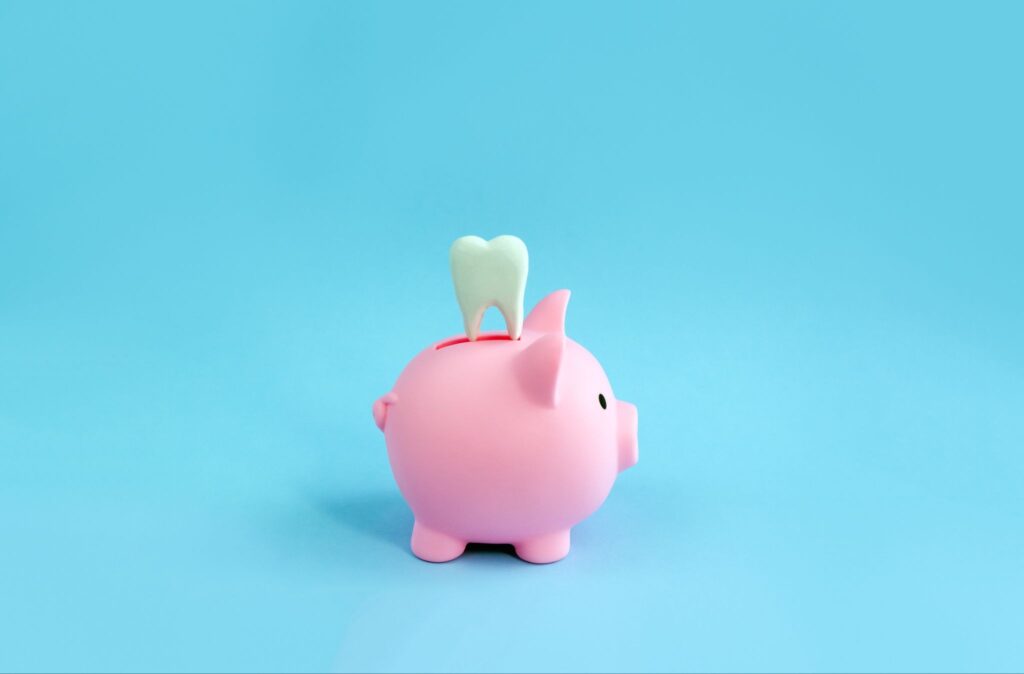 ブタの貯金箱の上に歯の模型が乗っている