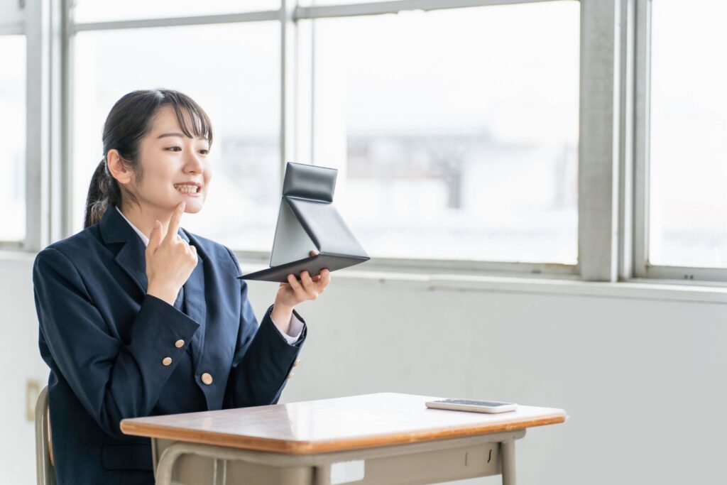 鏡で歯並びをチェックしている女子高生