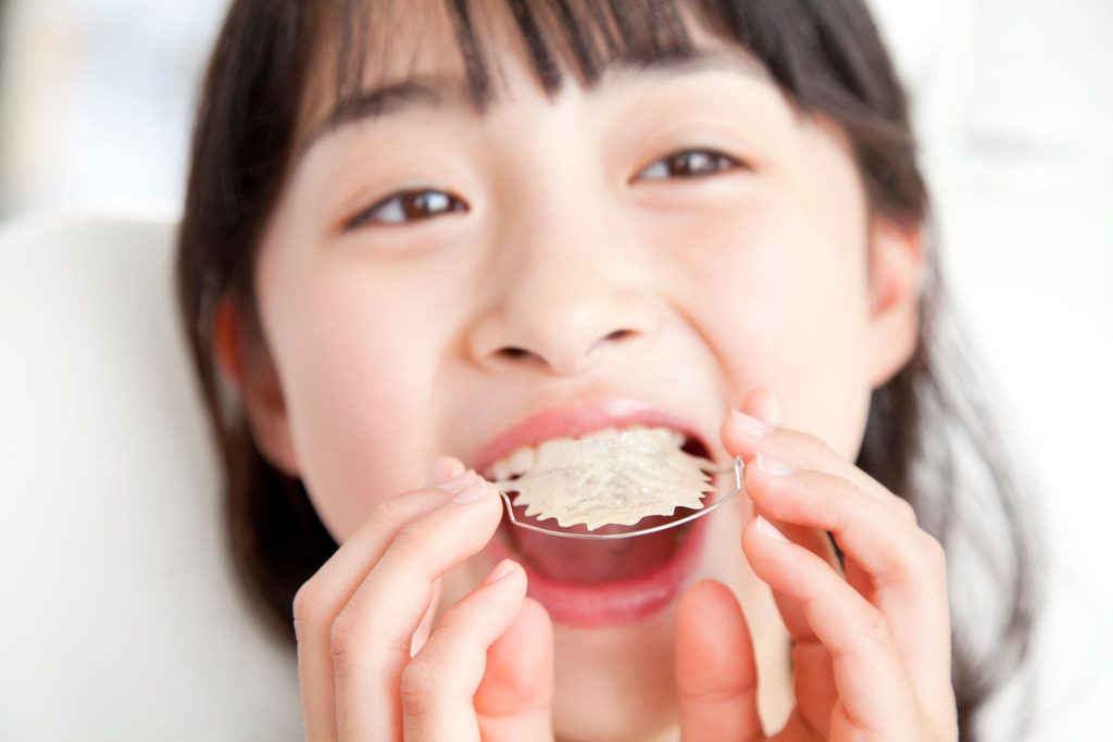 矯正装置を口の中に入れようとしている子供