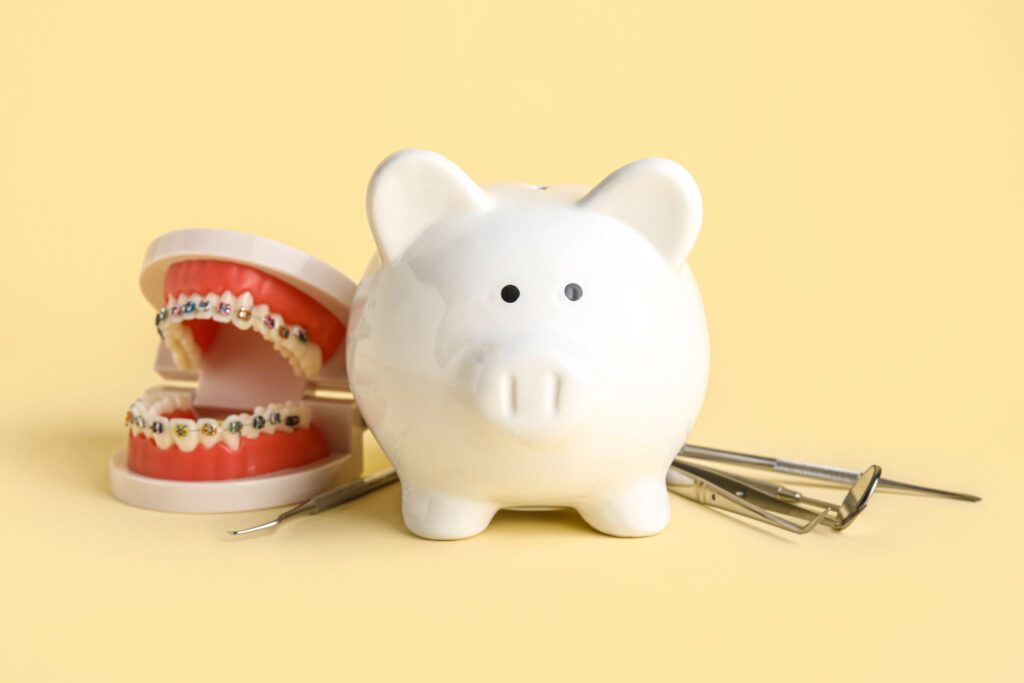 ブタの貯金箱とワイヤー矯正器具のついた歯の模型、歯科治療器具