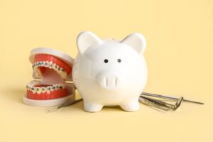ブタの貯金箱とワイヤー矯正器具のついた歯の模型、歯科治療器具